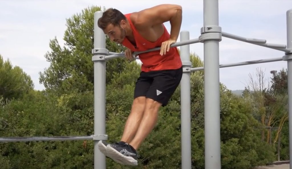 Homme passant sa tête au dessus d'une barre de traction pour réussir la dernière étape du muscle up