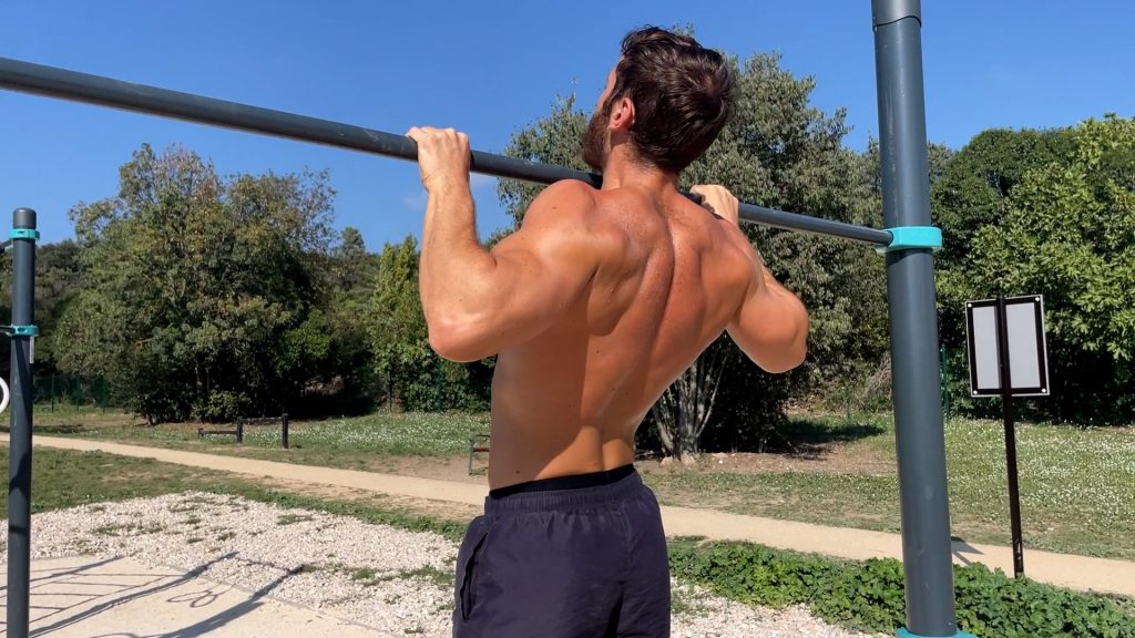 Homme faisant des tractions avec la tête au-dessus de la barre dans un parc de Street Workout