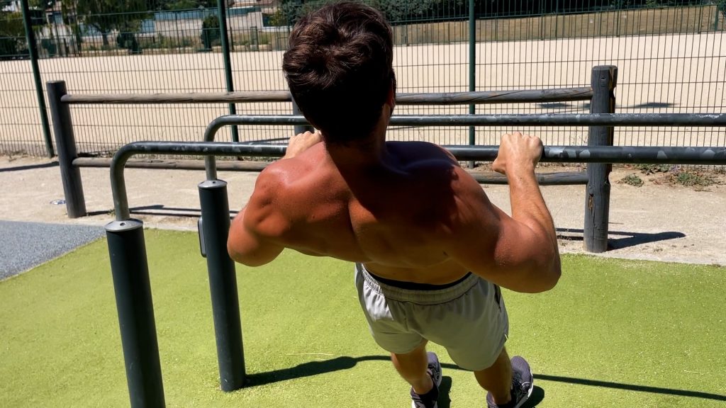 Homme de dos faisant des tractions australiennes dans un parc de Street Workout