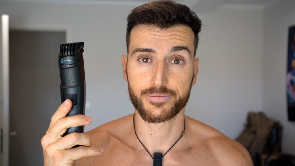 Homme de face souriant avec une tondeuse à la main pour se raser les cheveux