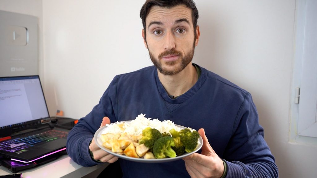 Homme sportif qui montre une assiette de poulet, riz et brocolis