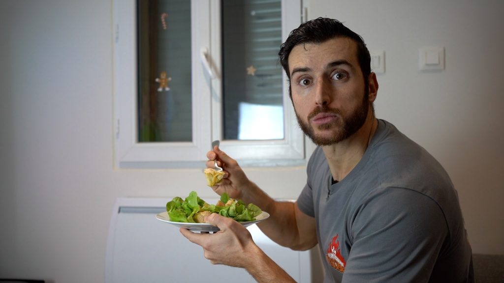 Homme de profil qui fait une tête d'étonnement en mangeant une assiette de poulet avec de la salade