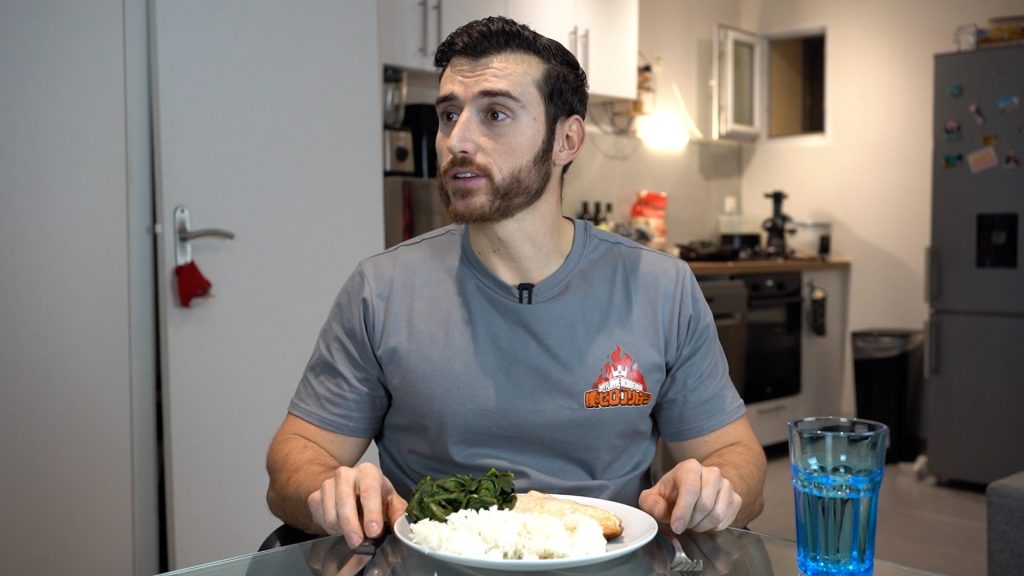 Homme assis à table qui est prêt à manger une assiette avec du saumon, du riz et des brocolis