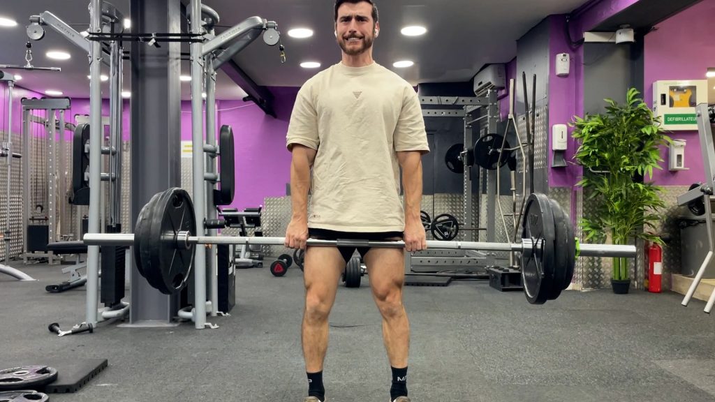 Homme grimaçant en train de faire du soulevé de terre dans un gym
