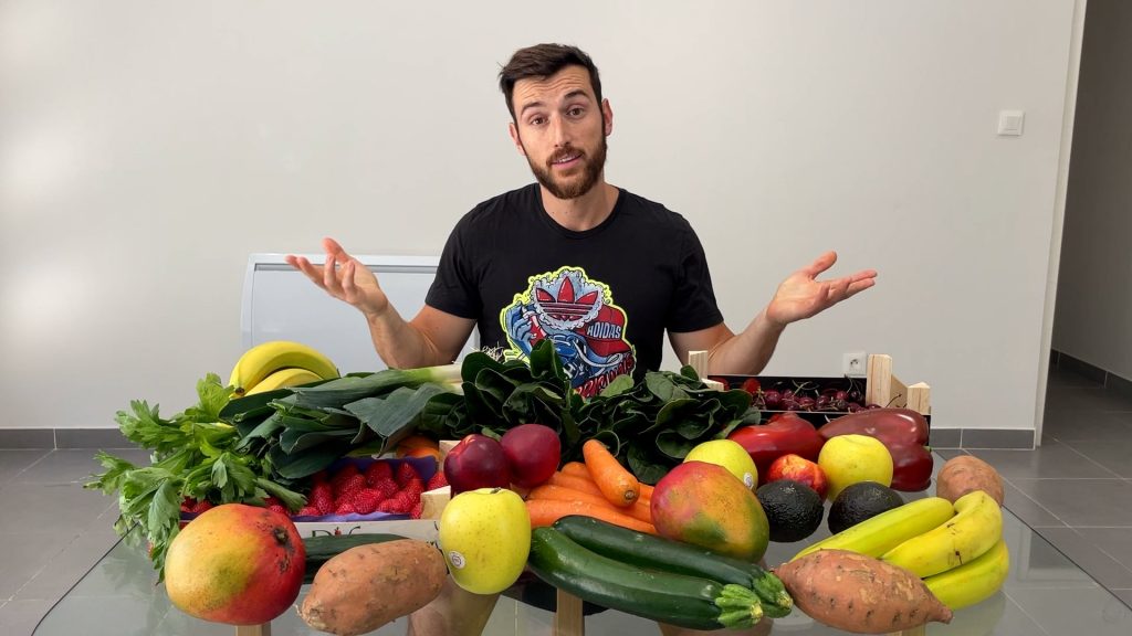 Homme assis derrière une table remplie de fruits et de légumes