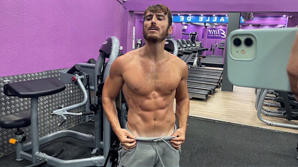 Homme musclé et sec prenant la pose devant un miroir de salle de sport